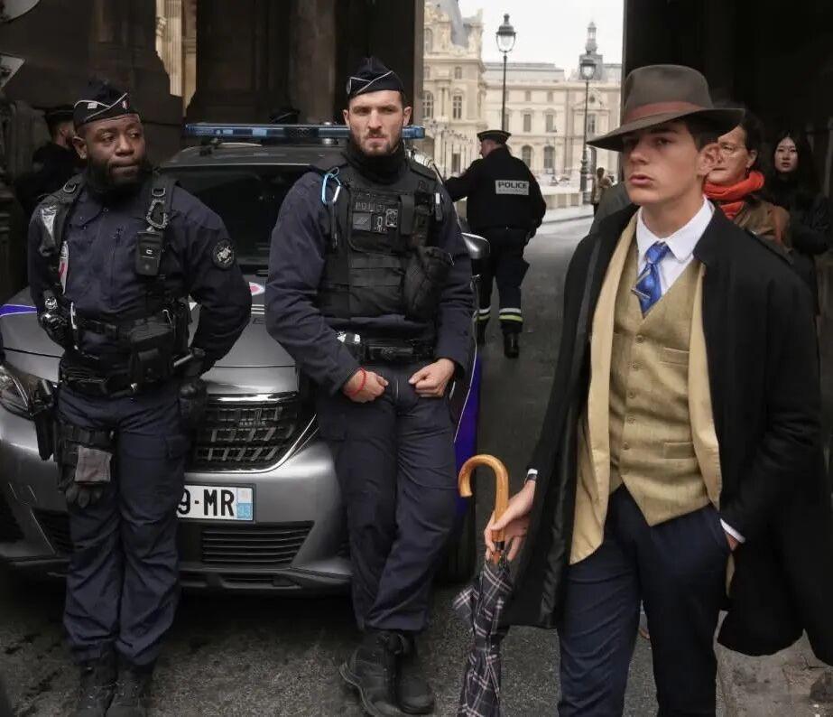 照片中，一位头戴费多拉礼帽（fedora）、身着三件套西装的年轻男子，风度翩翩地