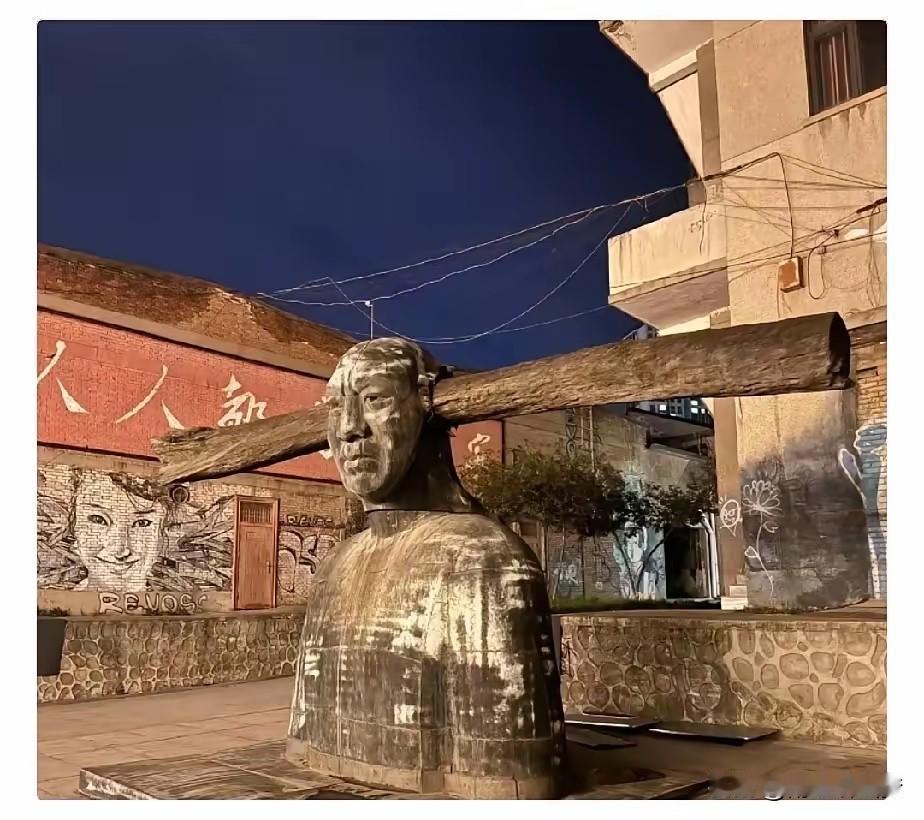 这雕塑是要给谁添堵？！

好家伙，一根粗木梁从人像脑袋穿进去，直挺挺地戳出来，远