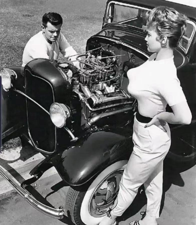 国外一男子帮美女司机维修汽车，女子穿着好笑又夸张
这张照片来自上世纪50年代，美
