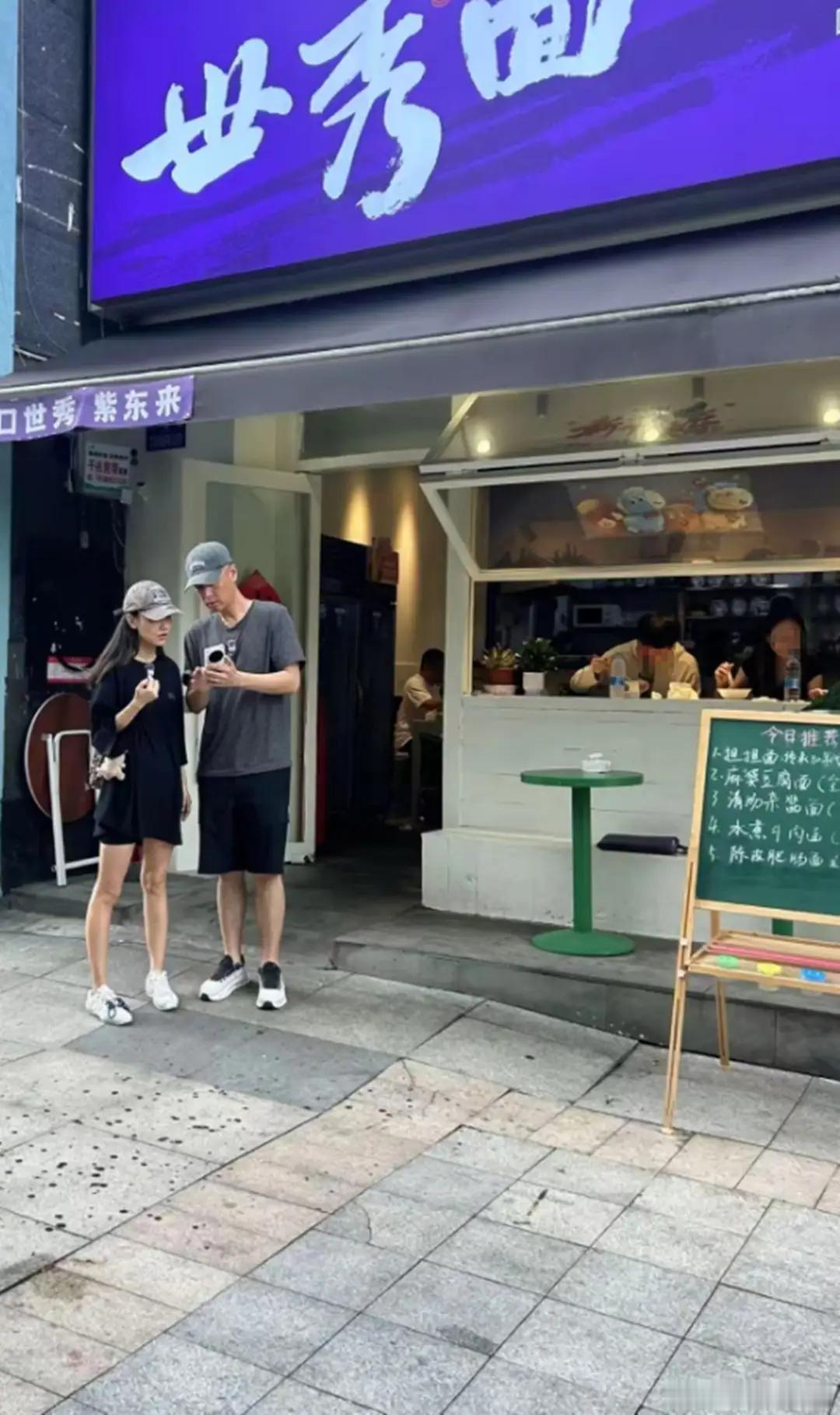 重庆街头偶遇任重夫妻俩啦！两人在面馆门口凑着看手机，互动超甜蜜。孙骁骁素颜出镜，