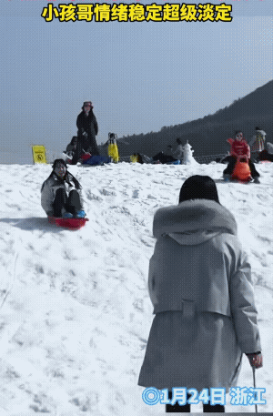 女生滑雪下来时，撞上了正在吃劲儿向上的小孩哥，结果抱着小孩哥滑了下来。
女生对小