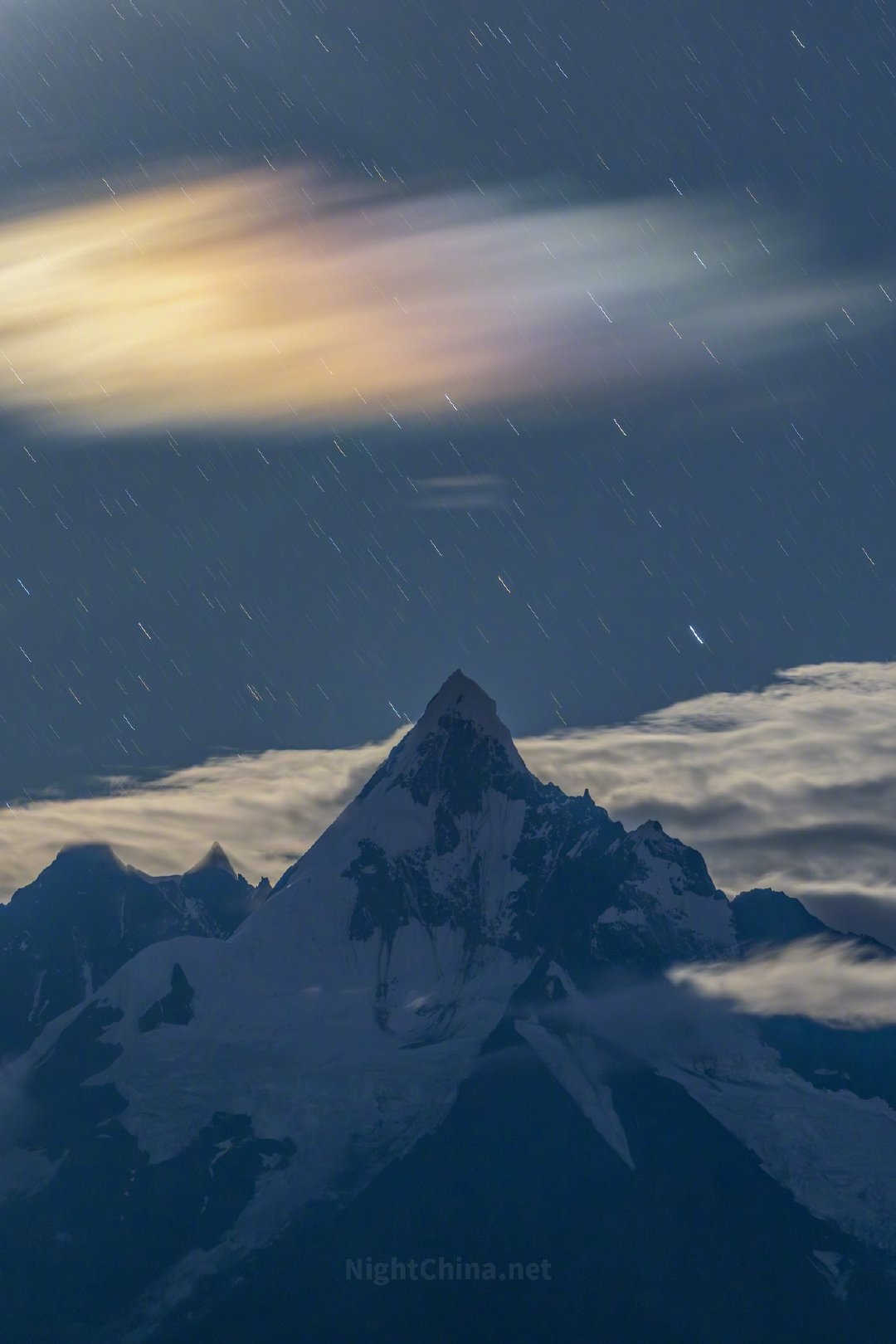 缅茨姆峰静伫于云海之巅，在月光的轻抚下愈显圣洁。苍穹之上，星辰被时光拉伸成细碎的