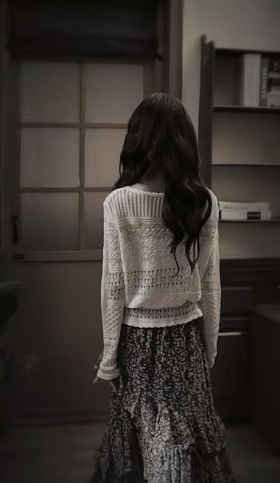 一个女孩背对着镜头，站在房间里。