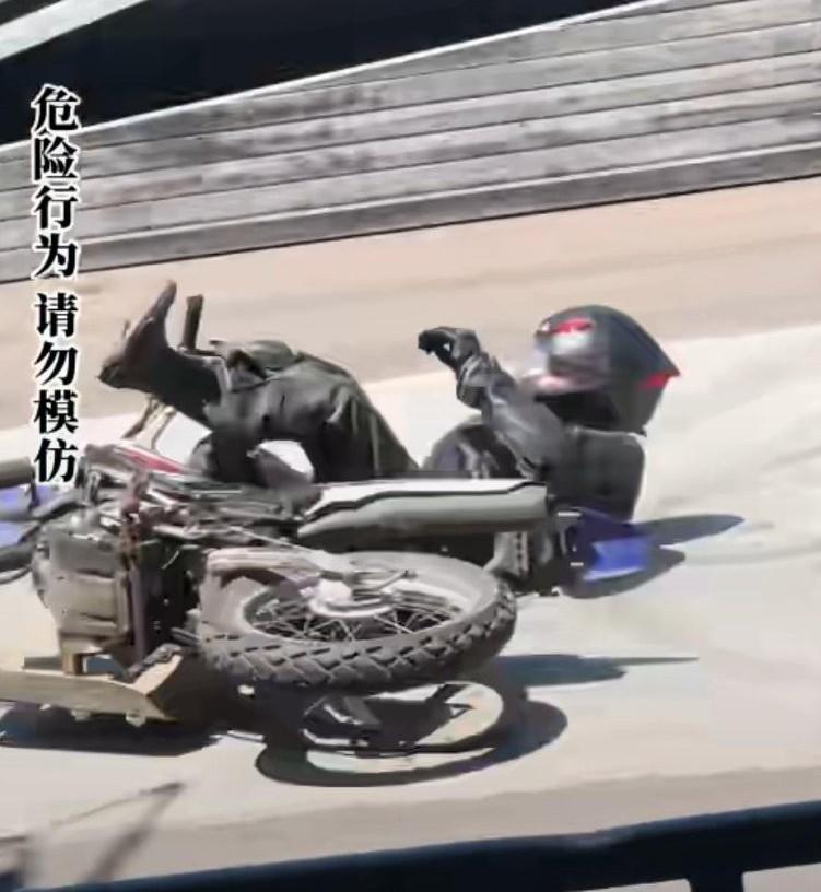 车手骑行途中摔倒后背着火，只见他慌乱中跑起来，后背带着火，
他竟然想爬过栏杆，
