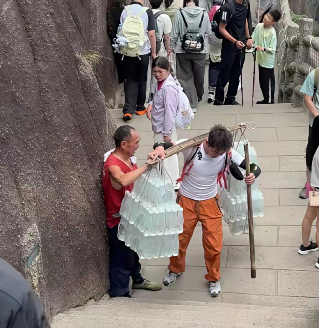 7月28日，安徽黄山，一90后小伙爬黄山途中，遇到一挑山工，扁担两头挑了满满的矿