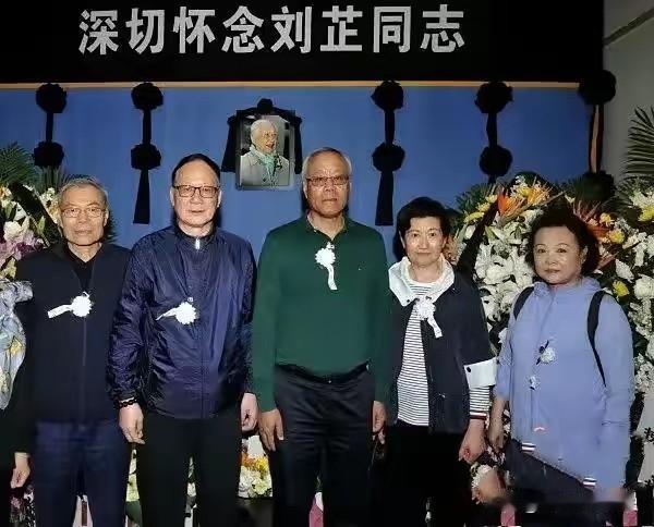 肃穆的告别现场，上方悬挂着“深切怀念刘芷同志”的大字，花束整齐摆放，氛围庄重哀沉
