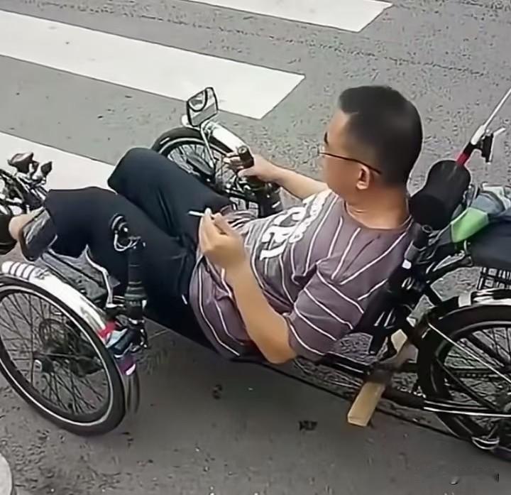 马路上的这一幕，让人又羡慕又捏汗。男子躺在一辆特制的三轮躺车上，姿势松弛得像窝在