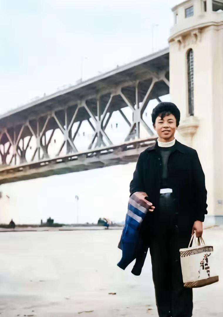 一个人站在桥下，手拿外套和袋子。1958年留下了一张珍贵照片。还有多少人记得他呢