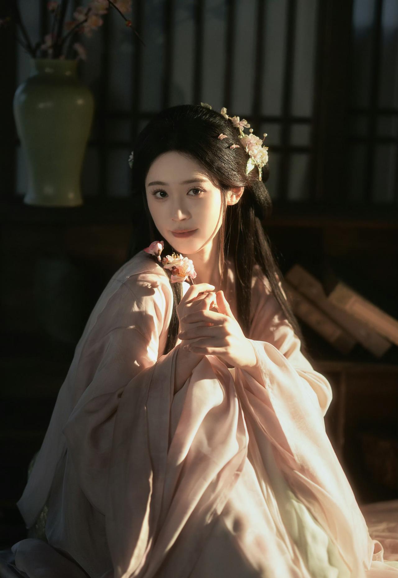 窗棂漏下的柔光，轻笼着一室清浅。她执花静坐，任花香与烛火漫过衣襟，将时光都揉成了