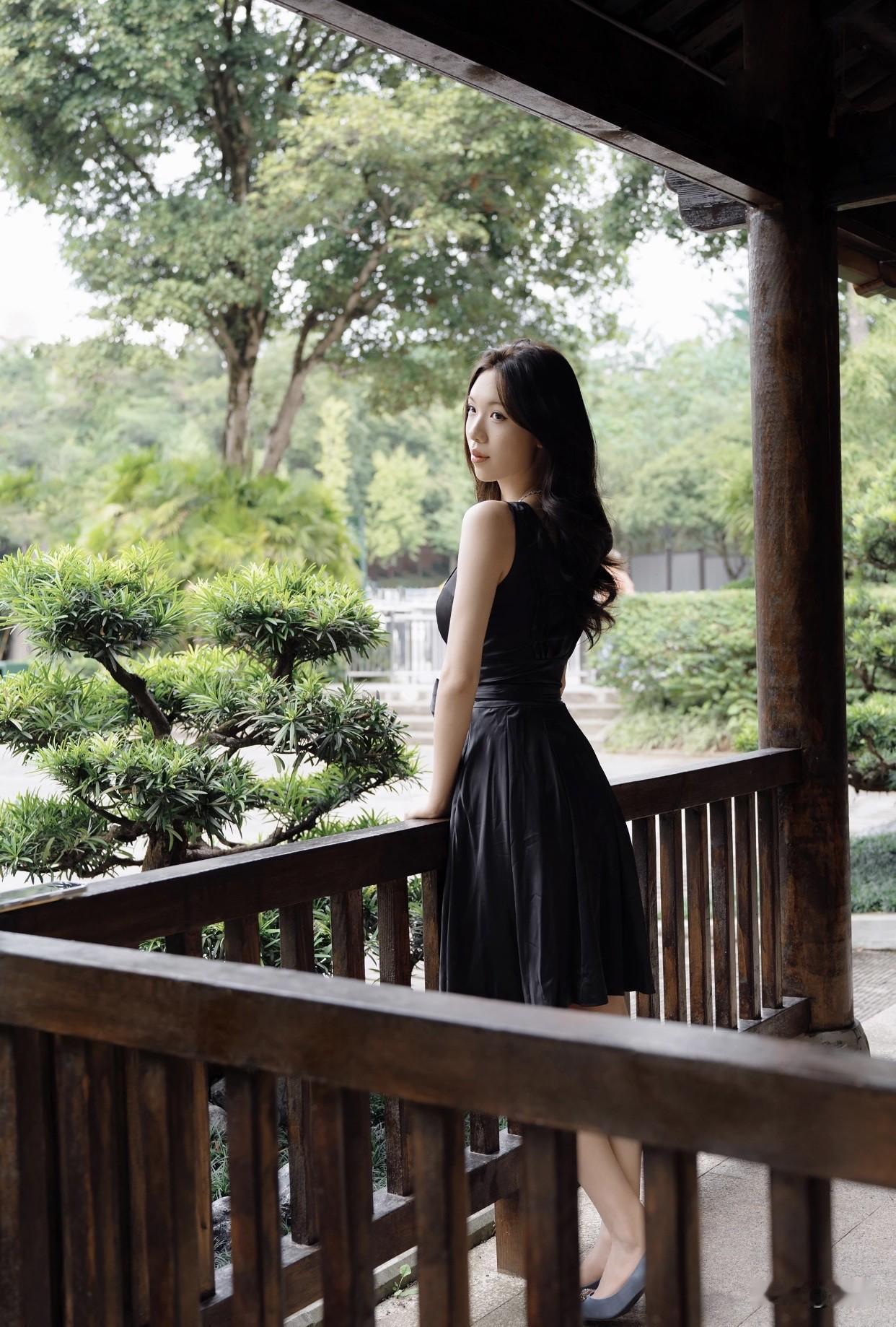 共享美人靓照优雅黑裙与自然绿意相映成趣，静坐石边，沉思时光。