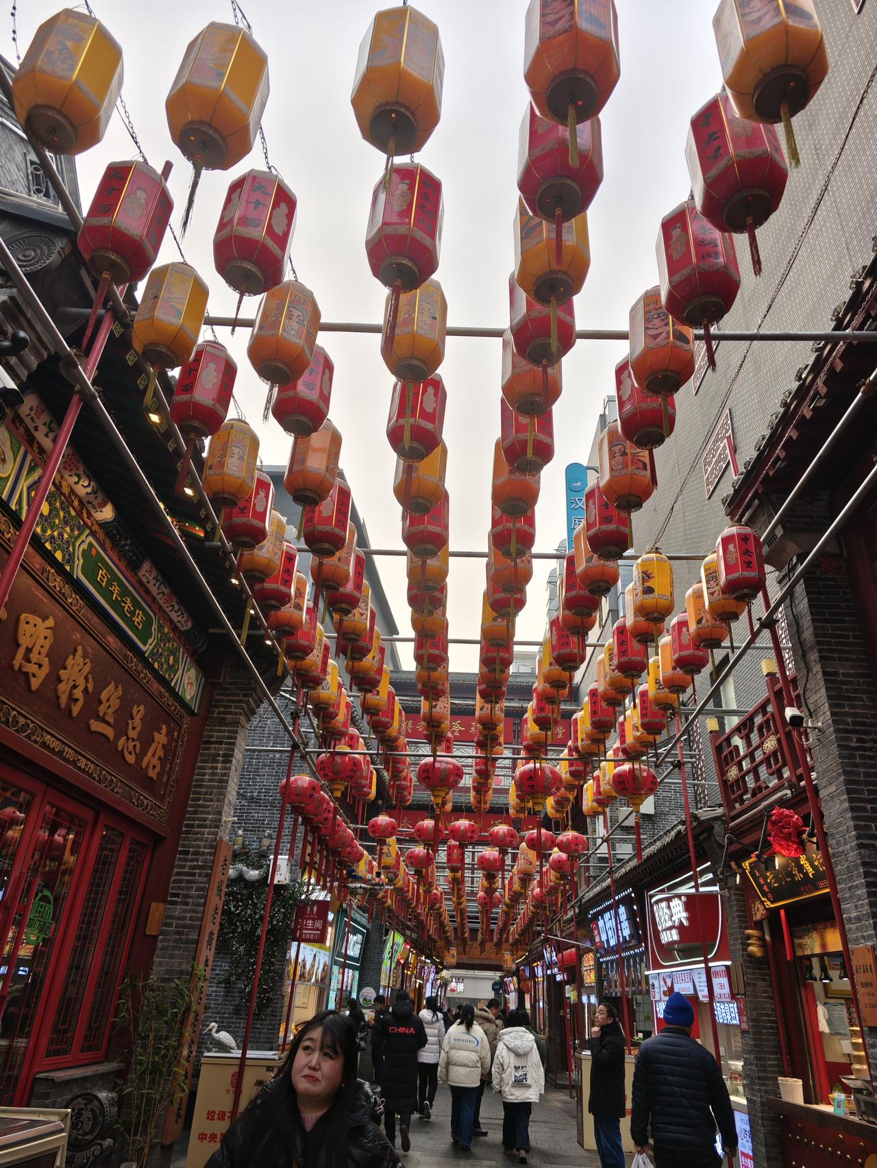 分享一下你随手拍下的照片腊月的老街被红黄灯笼织成了穹顶，青砖黛瓦衬着朱红门脸，烟