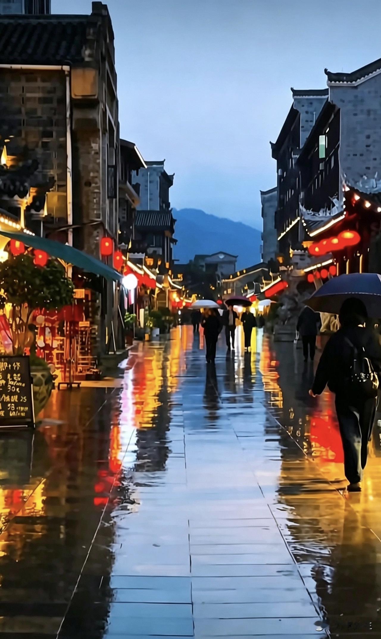细雨浸润青石板，暖黄灯火倒映在积水的长街，行人撑伞缓缓而行，古镇的夜色，就这样安