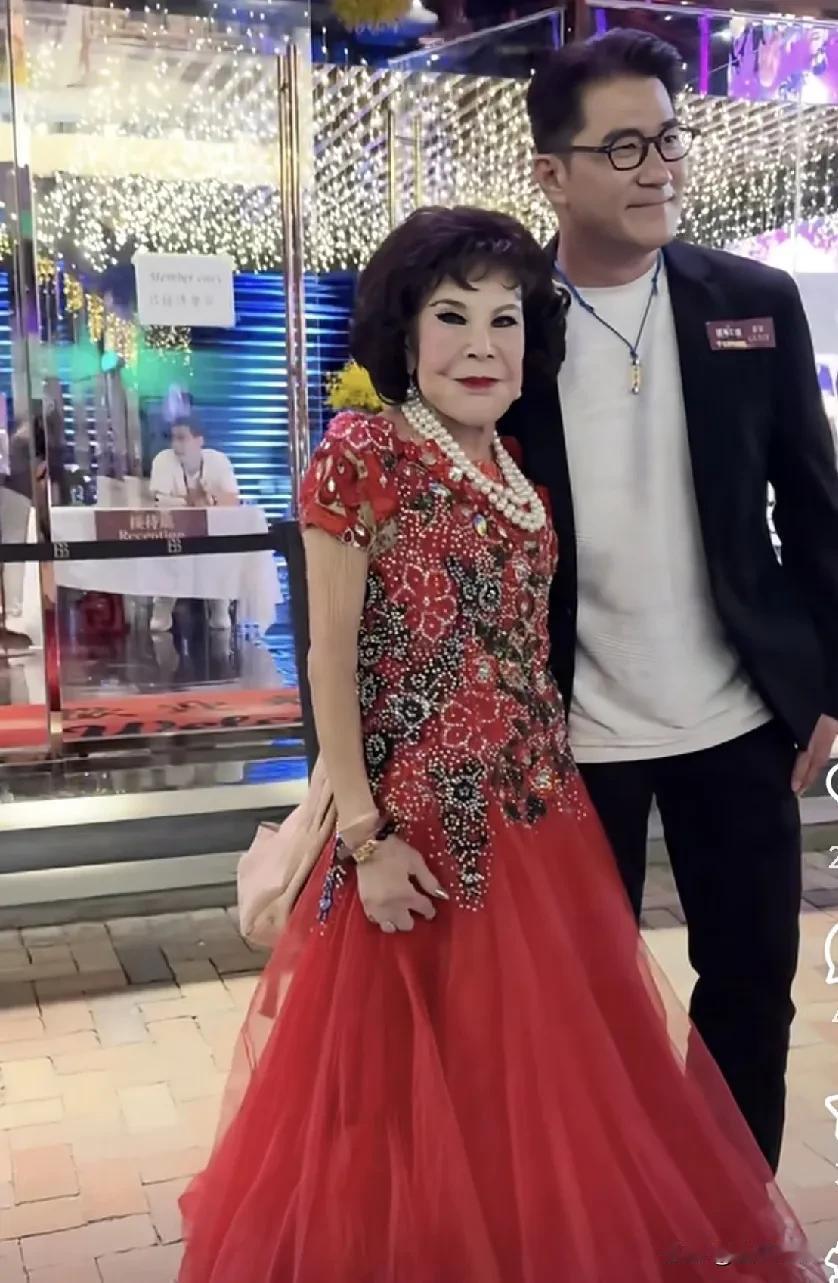 这位穿红色连衣裙的大妈是黄夏蕙 ，是香港的资深艺人，活跃于演艺圈等领域，以独特的