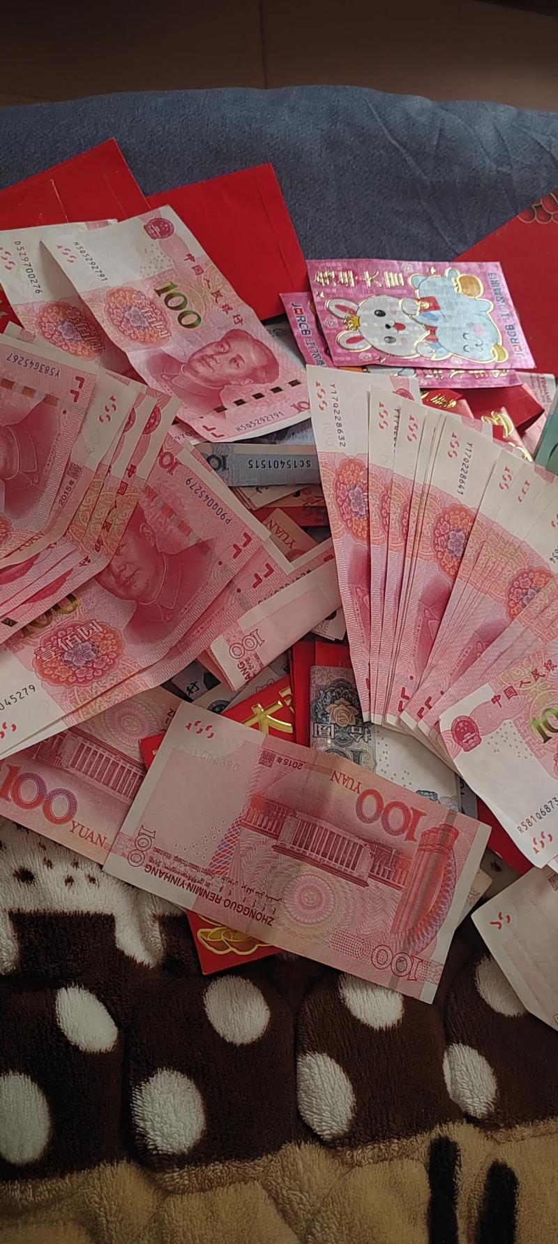 2月21日江苏，一父亲让儿子清点压岁钱准备存银行，培养其理财观念。儿子认真数着，