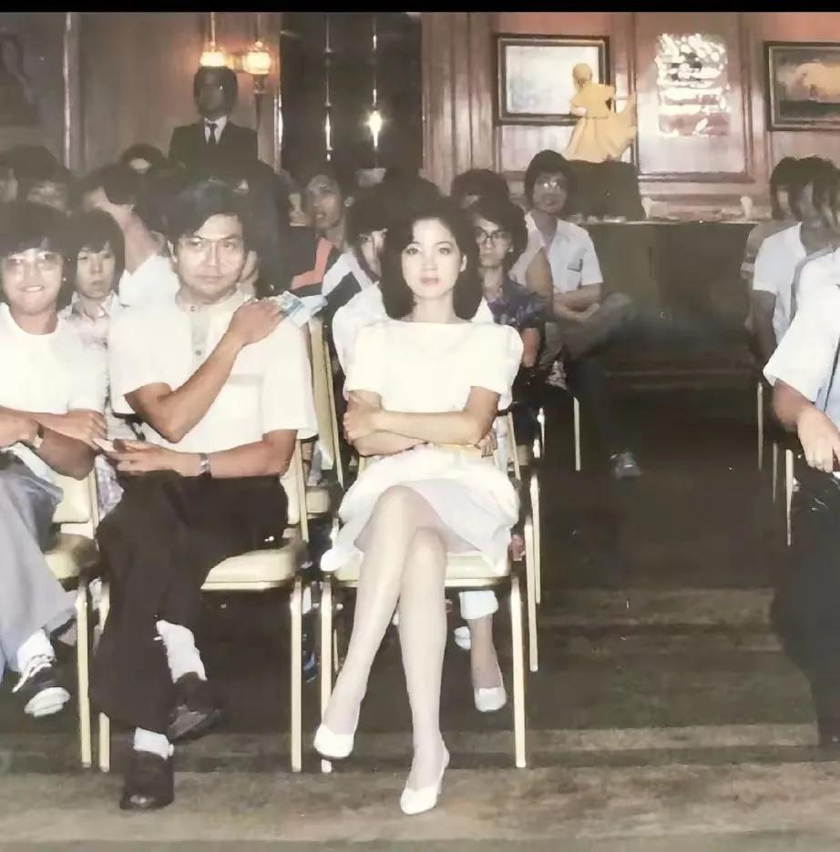 大家看这是1981年4月在香港，邓丽君在观赏节目，旁边那位男子却坐在了中间，大家