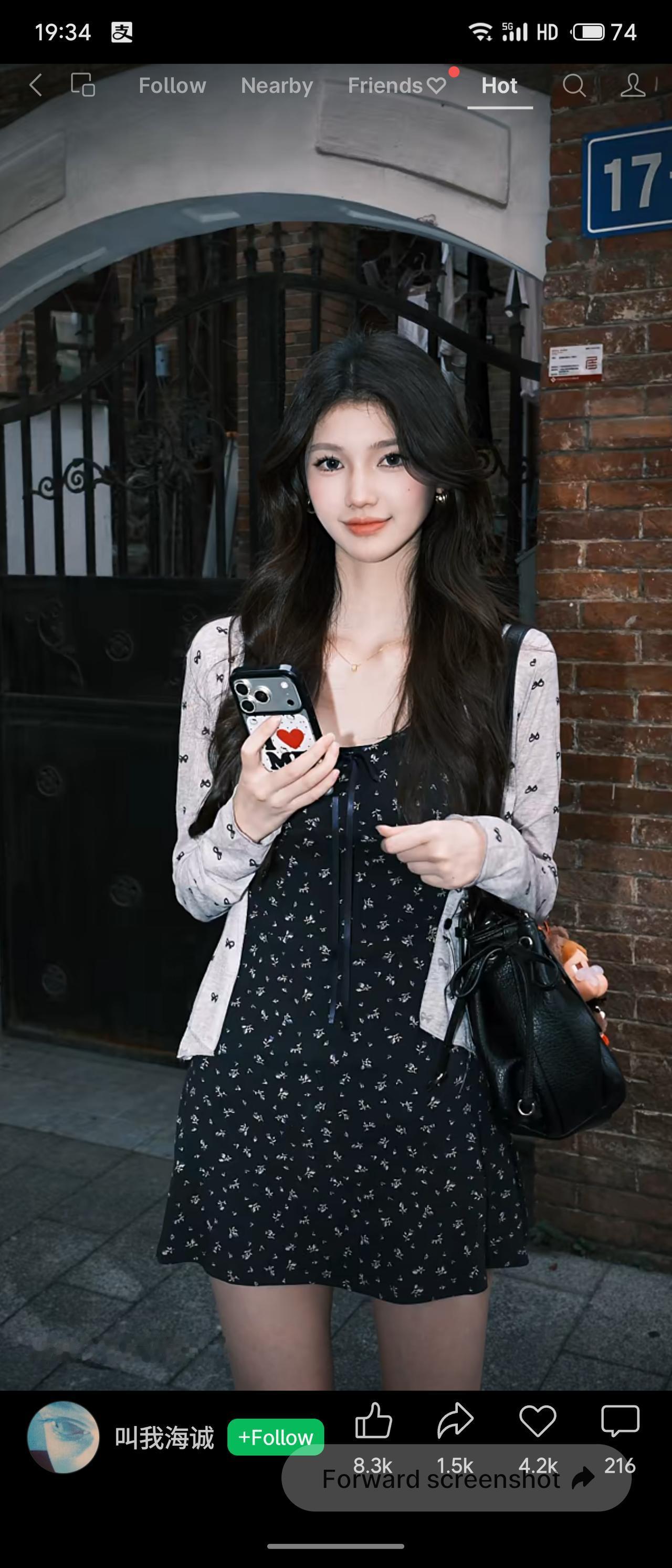 广州老巷红砖门楼下，少女吴淑仪氛围感十足。黑底碎花吊带短裙勾勒纤细身形，外搭印满