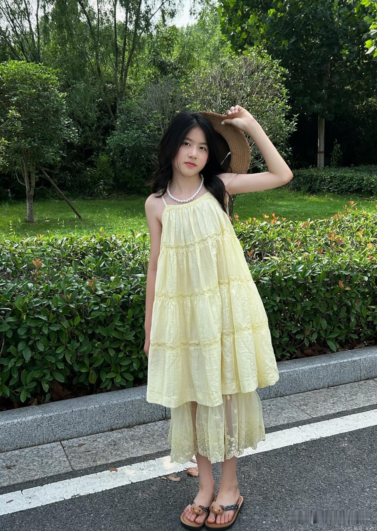 小妹妹穿着黄色连衣裙在路边拍照。