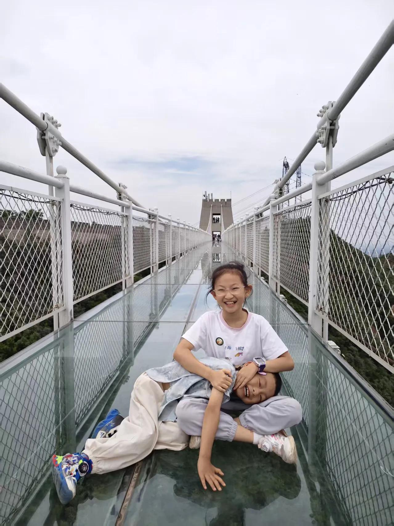 姐姐放缓脚步，轻声安抚他，带着他一点点向前挪动。起初弟弟目光不敢向下张望，慢慢在
