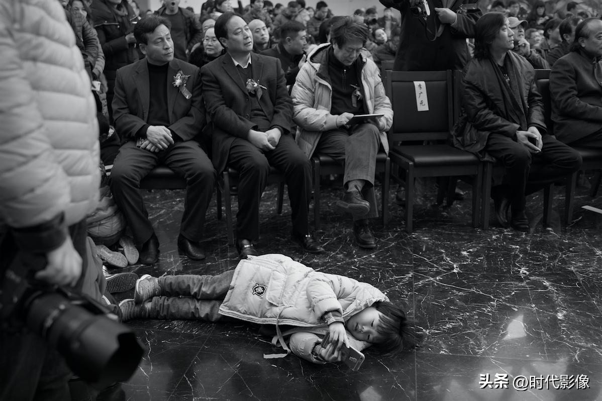 正在主席台位置为一个展览的开幕式拍照，低头一看发现这个完全沉浸在手机世界里的小姑