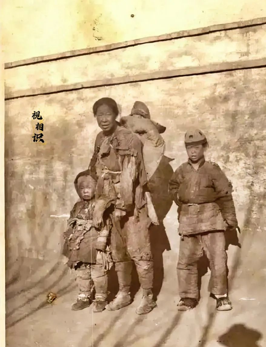 1925年，北平，一位母亲带着三位孩子的老照片，四人身处墙角，衣衫褴褛，大儿子已...