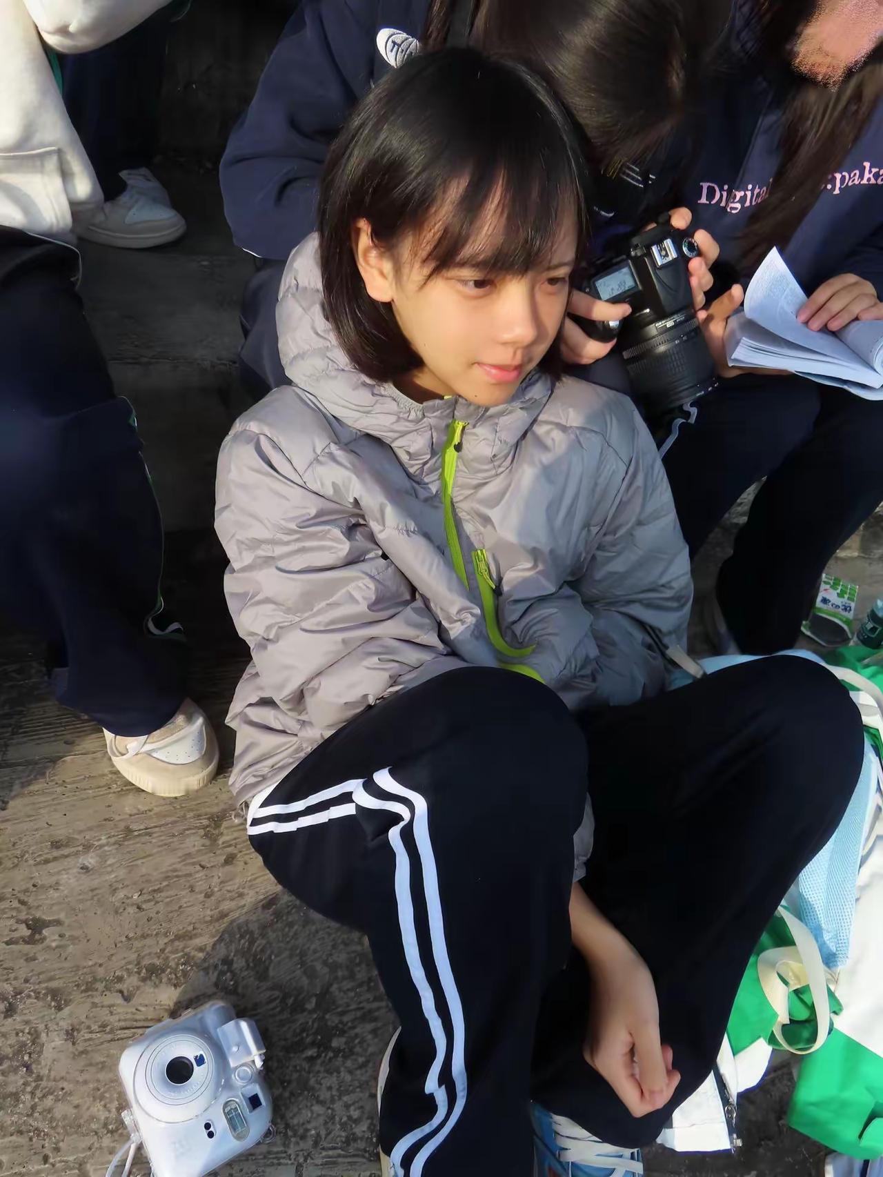 一群孩子坐在地上，一个女孩看着相机。超有镜头的女孩 躺地上的小孩 看书的小孩儿