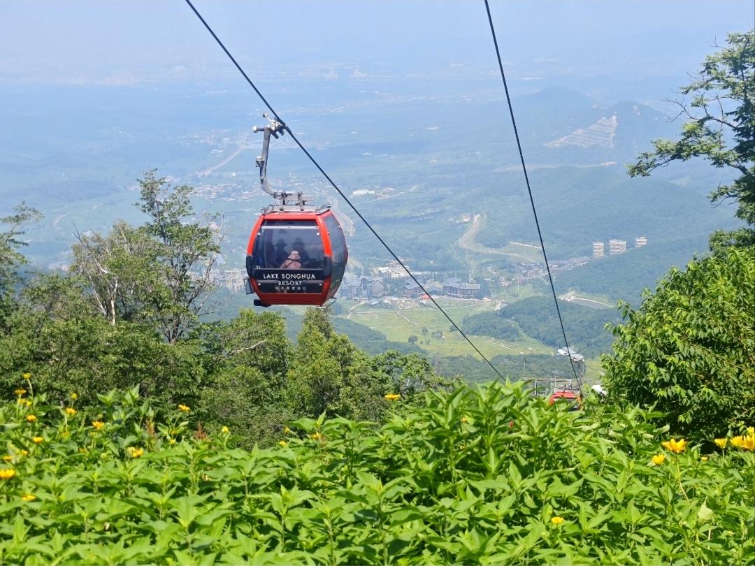 乘坐缆车，缓缓升向中旅松花湖青山之巅，满目盛夏山林铺展的翠绿。

极目远眺，连绵