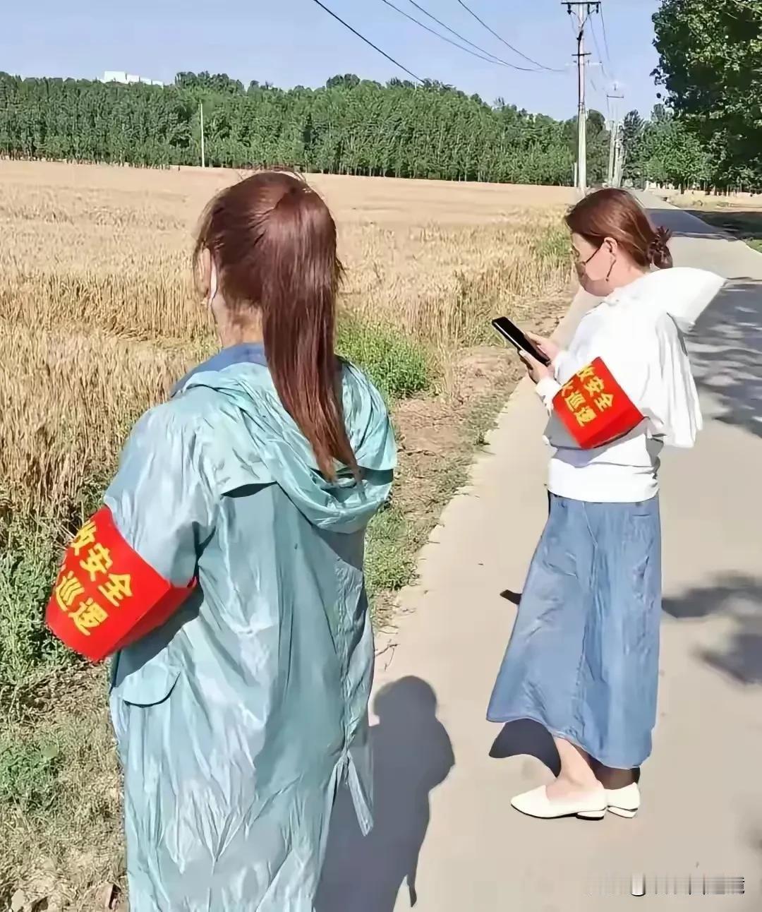乍一看，还以为照片中这两个美女在田间地头搞直播，她们的左手手臂上戴着红袖章，原来