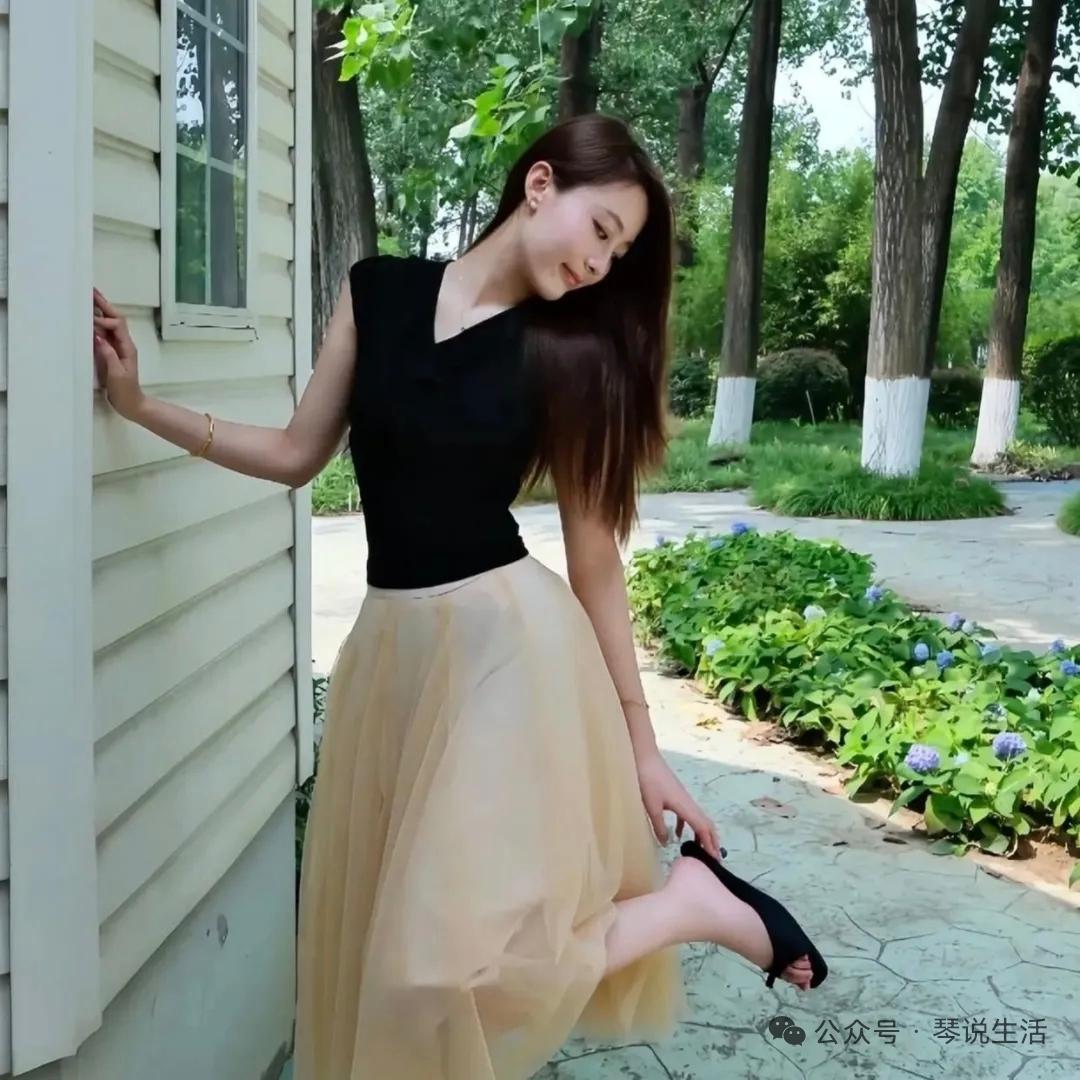 她靠在墙边，穿着黑色上衣和长裙，显得优雅又自在。