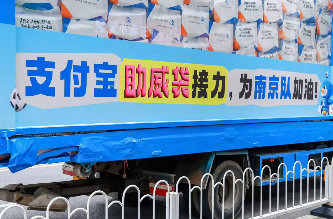 苏超助威袋坐着卡车来南京了 满满心意的助威袋乘卡车上演街头“快闪”。流动应援超吸