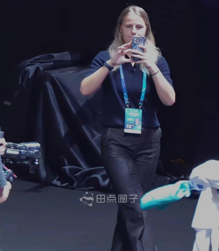 莎莎和高达比赛结束后发现一个有趣的现象。莎莎穿着外套拿着绿色大毛巾，大跨步朝前走