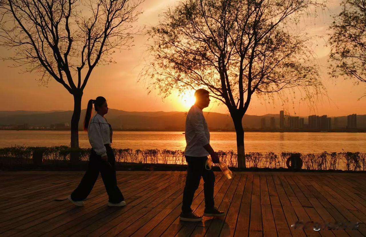 坐着湖边的条椅上，沐浴着红色的夕阳，看着太阳慢慢落下，使用相机记录下来个个剪影，