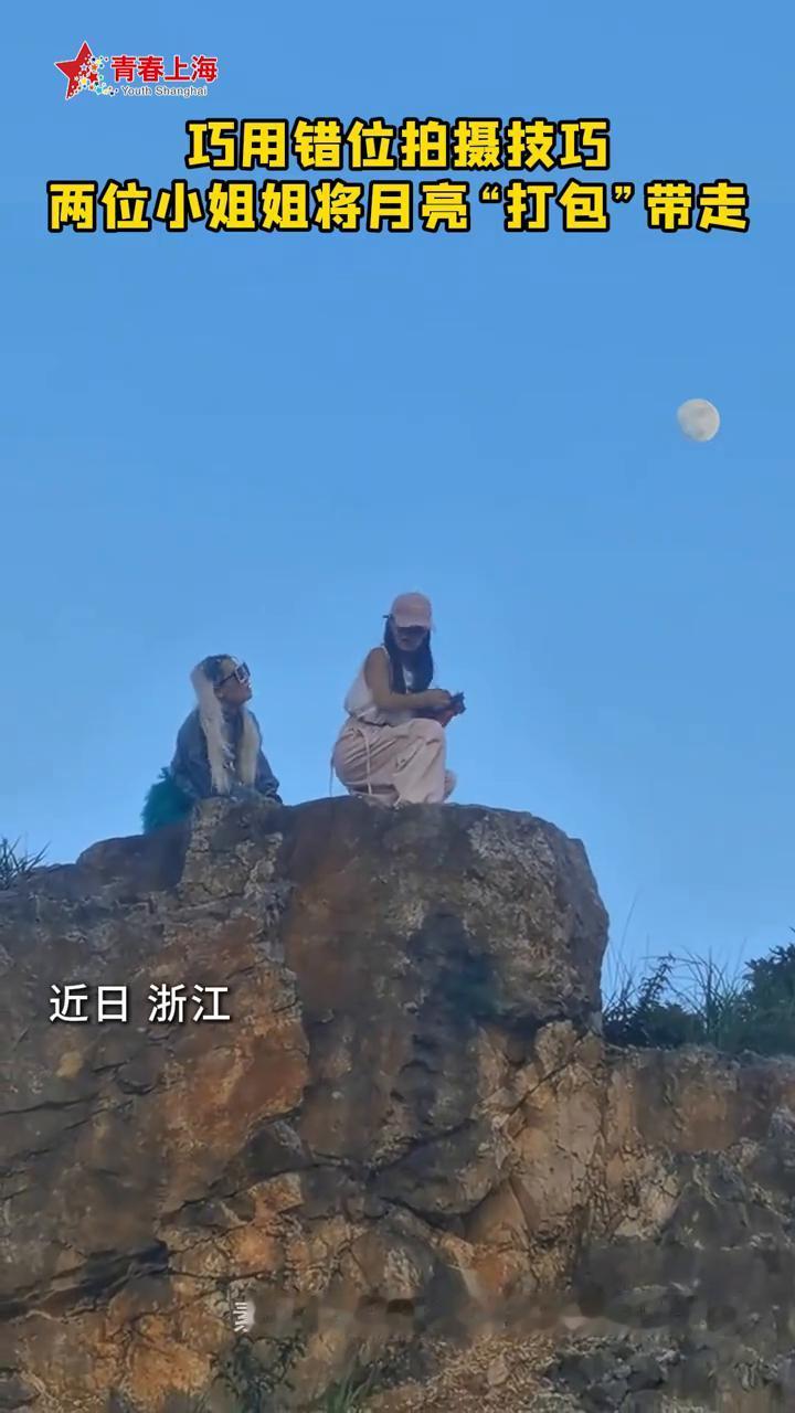巧用错位拍摄技巧，两位小姐姐将月亮"打包"带走。
趣看风景、环球时报。
近日浙江
