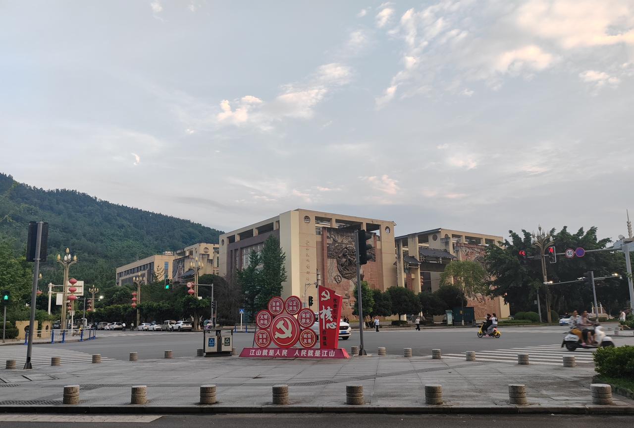 远山叠翠，云漫长空，街头的红色标语格外醒目。古朴浮雕建筑静静伫立，往来车辆慢行，
