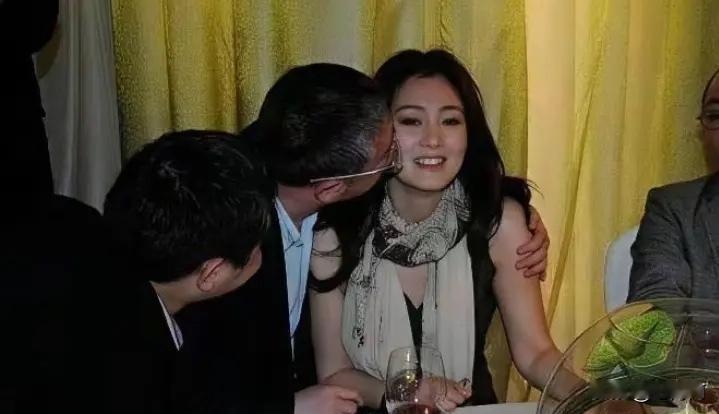 早年演员巩俐出席宴会时的一幕，不知道这位搂着她的男子是谁，让巩俐强颜欢笑，还挺尴