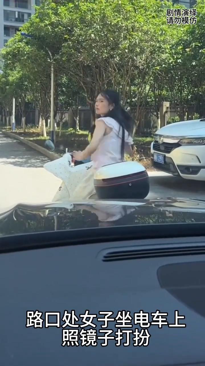 路口处女子坐电车上照镜子打扮，这时后面车子按喇叭催促她，于是女子生气瞪车主，下一