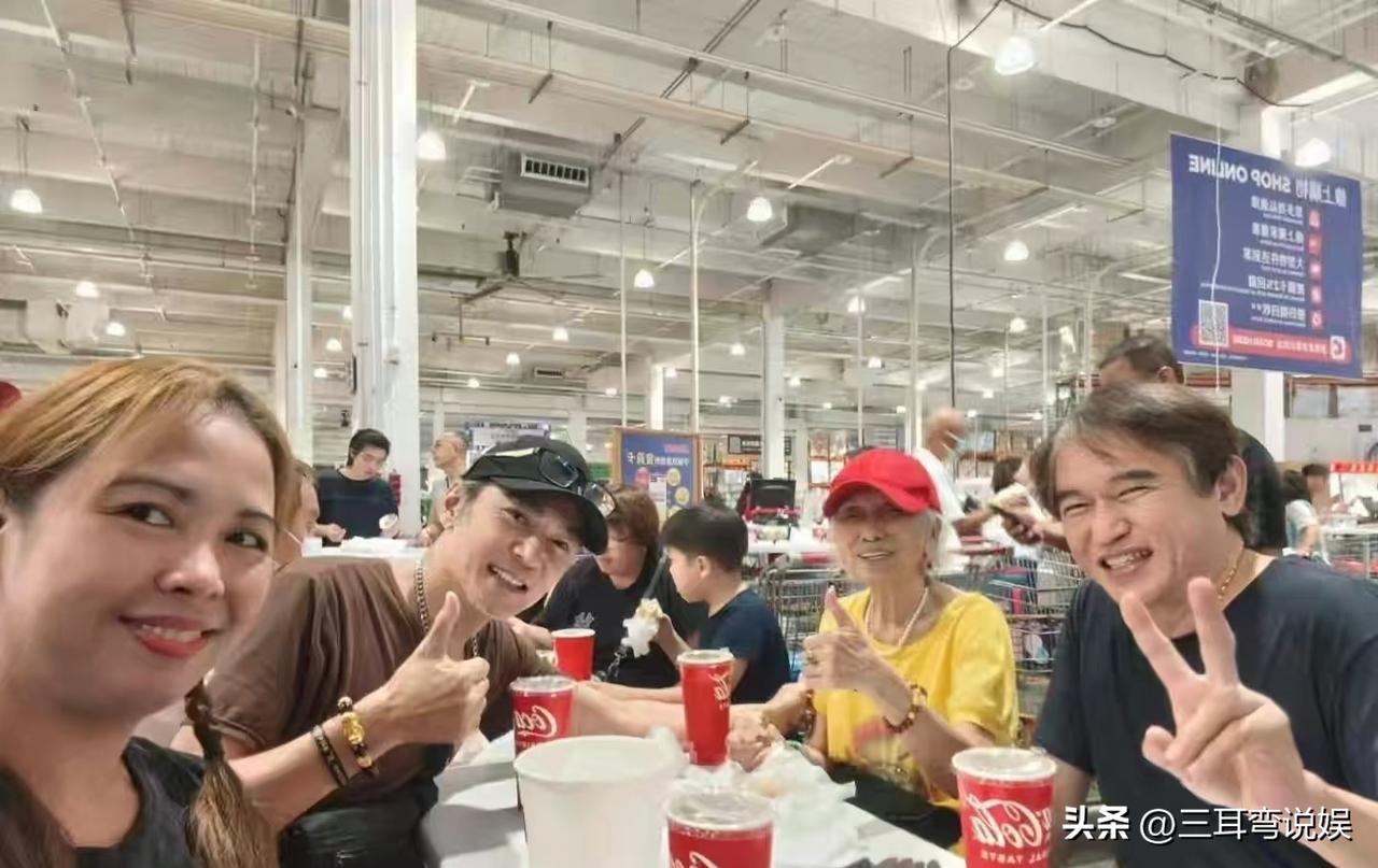 58岁的焦恩俊与妈妈和哥哥一起外出用餐，拍照时他笑容灿烂，一只手竖起大拇指，另一