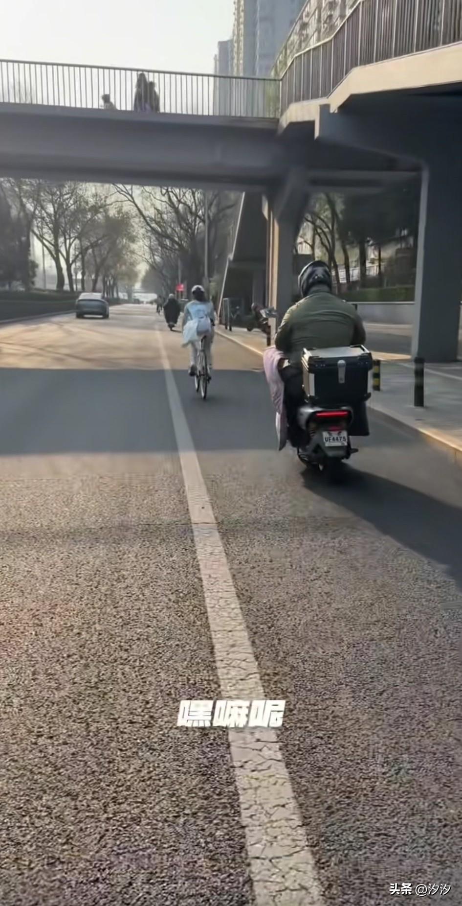 北京一大哥骑车发现有人，
拿着手机偷拍前面的女骑手，
女生穿着专业的骑行服，
躬