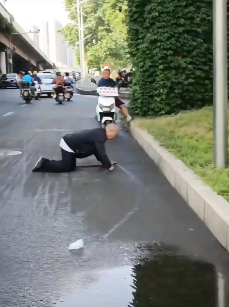 成都一位老大爷过马路摔倒，可能是因刚下过雨地面湿滑。摔倒地点是主干道，路人超多，