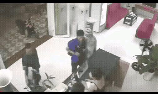 两个人在前台办理手续，一个背包男子不小心碰到了身后的一个大花瓶，男子转身想扶住花