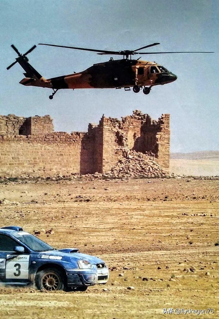 一架美国军用西科斯基UH-60黑鹰直升机从一辆斯巴鲁翼豹WRX STI拉力赛车旁