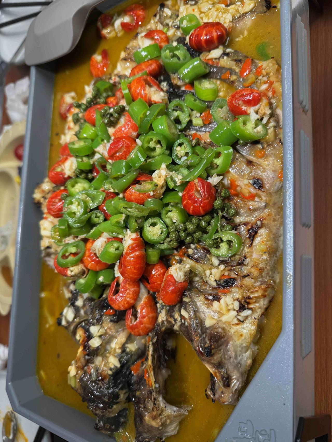 外皮烤得微焦，鱼肉依然鲜嫩多汁，青红辣椒铺满表面，香辣香气很突出，金黄汤汁浸着鱼