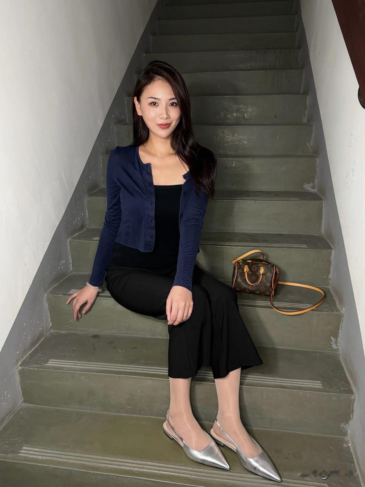 一位美女坐在楼梯上，手托着下巴。