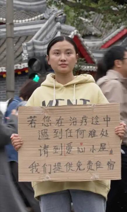 四川成都，华西医院门口有一个女孩子胸前举着一块牌子，写着提供免费住宿吃饭，很多人