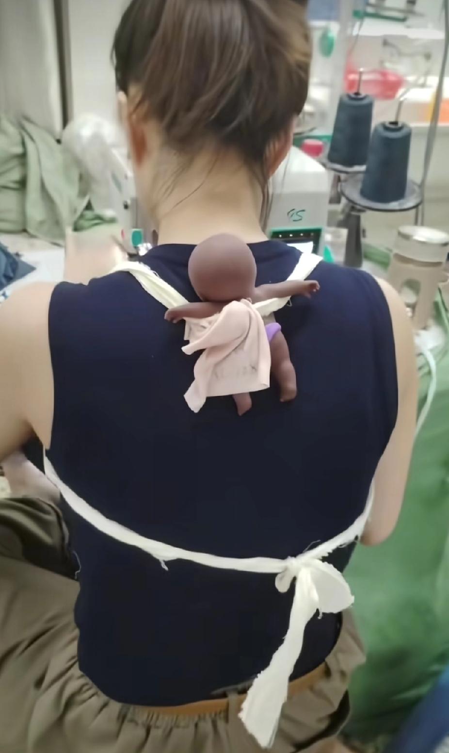 女子上班时，身上却总绑着根布带。看见女子的后背时，让人瞬间泪目了。

制衣车间里