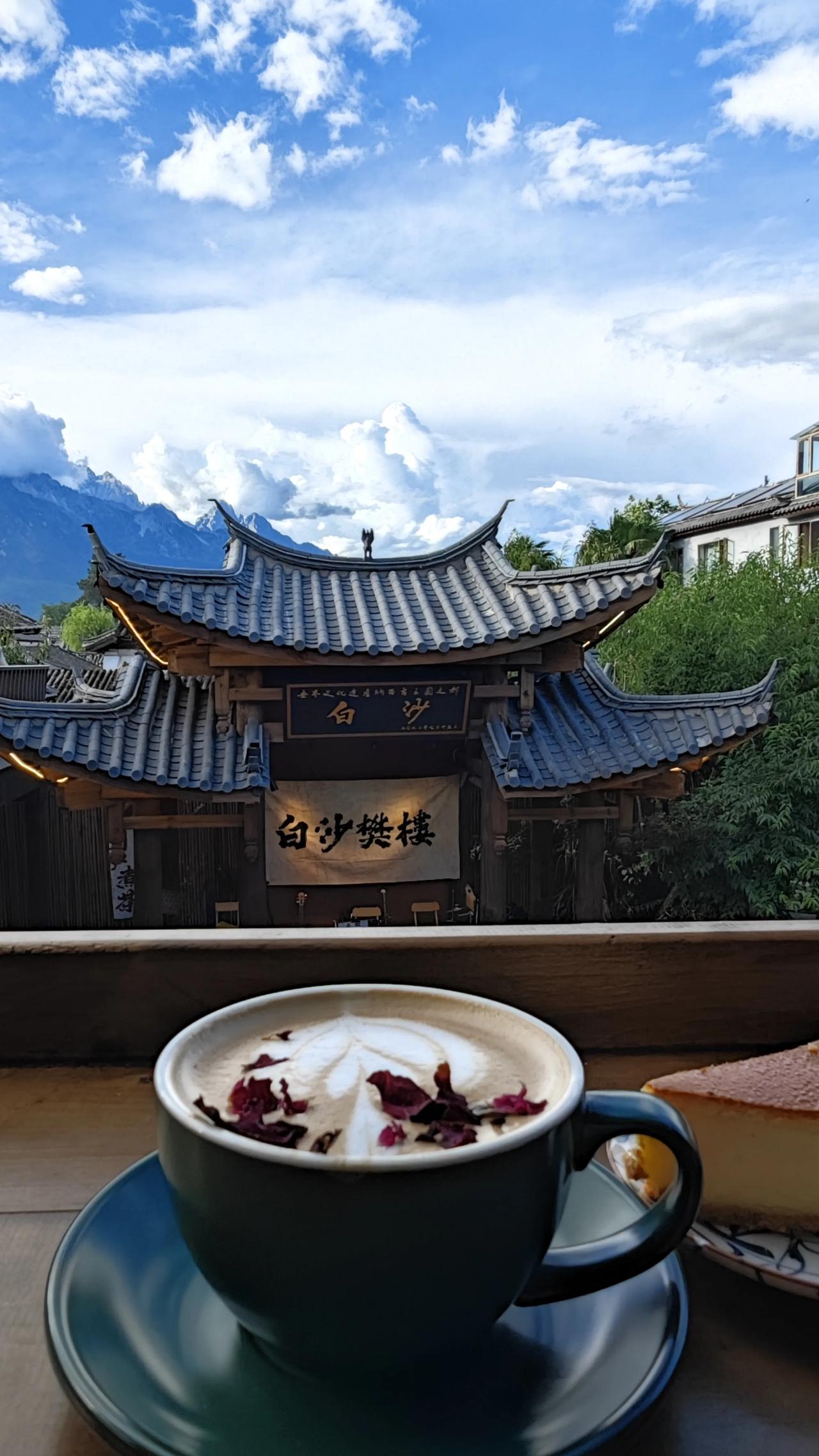 远处玉龙雪山静静矗立，苍穹如洗，白云悠然。手捧一杯温热的咖啡，氤氲的香气与微凉的