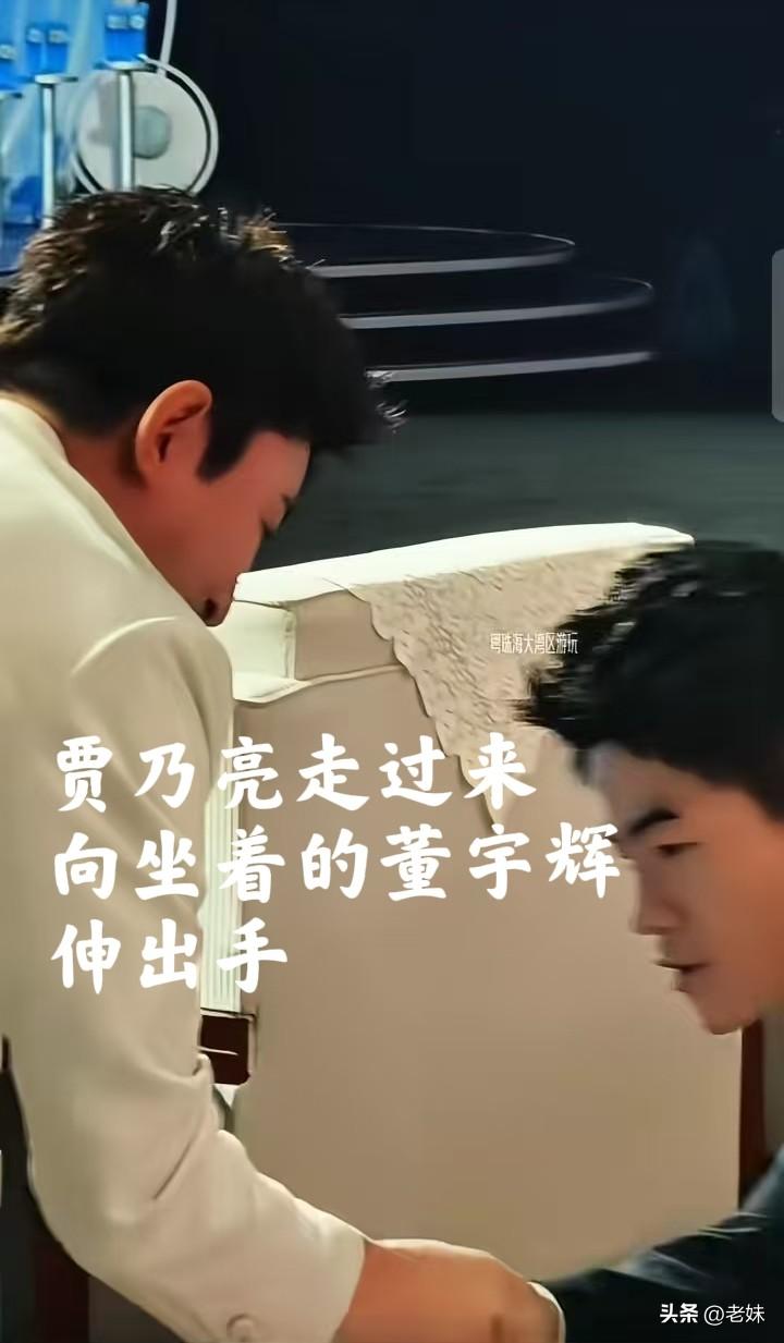 贾乃亮走过来，主动和坐着的董宇辉握手，贾乃亮谦逊微笑，董宇辉礼貌回应，请贾乃亮落