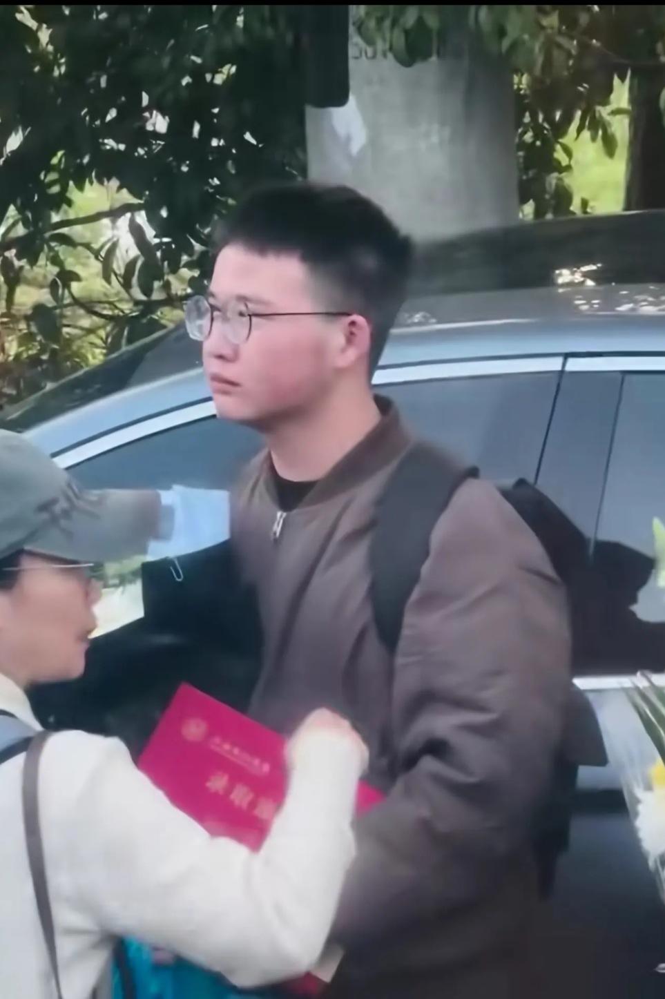 在送别现场
这个男孩除了手里抱着花，还有一本录取通知书，看着他哭红的眼眶，可能他