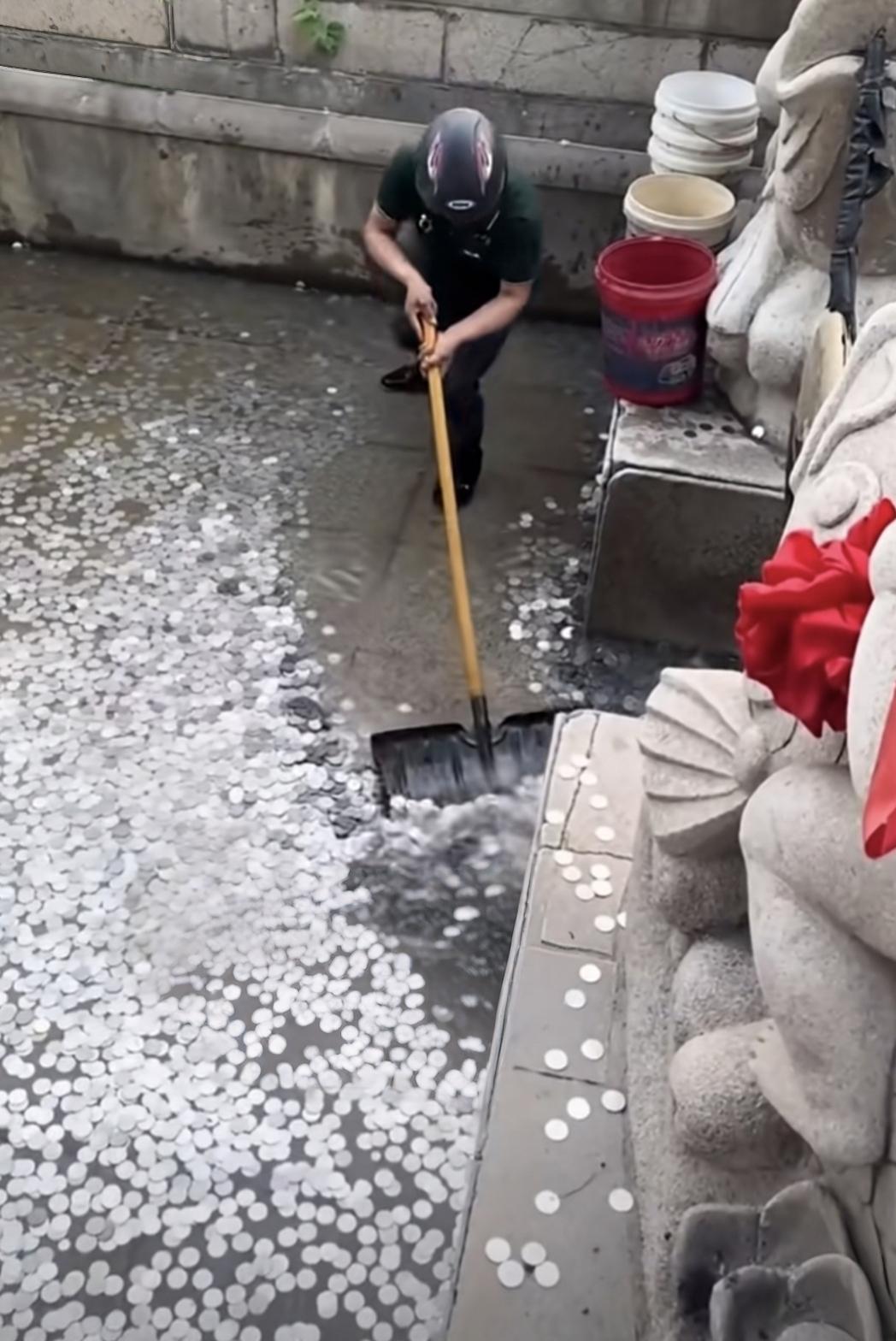 分享每日的感悟某庙宇“投币祈福池”中硬币满满，工人正用铁锹往5个塑料桶里装。