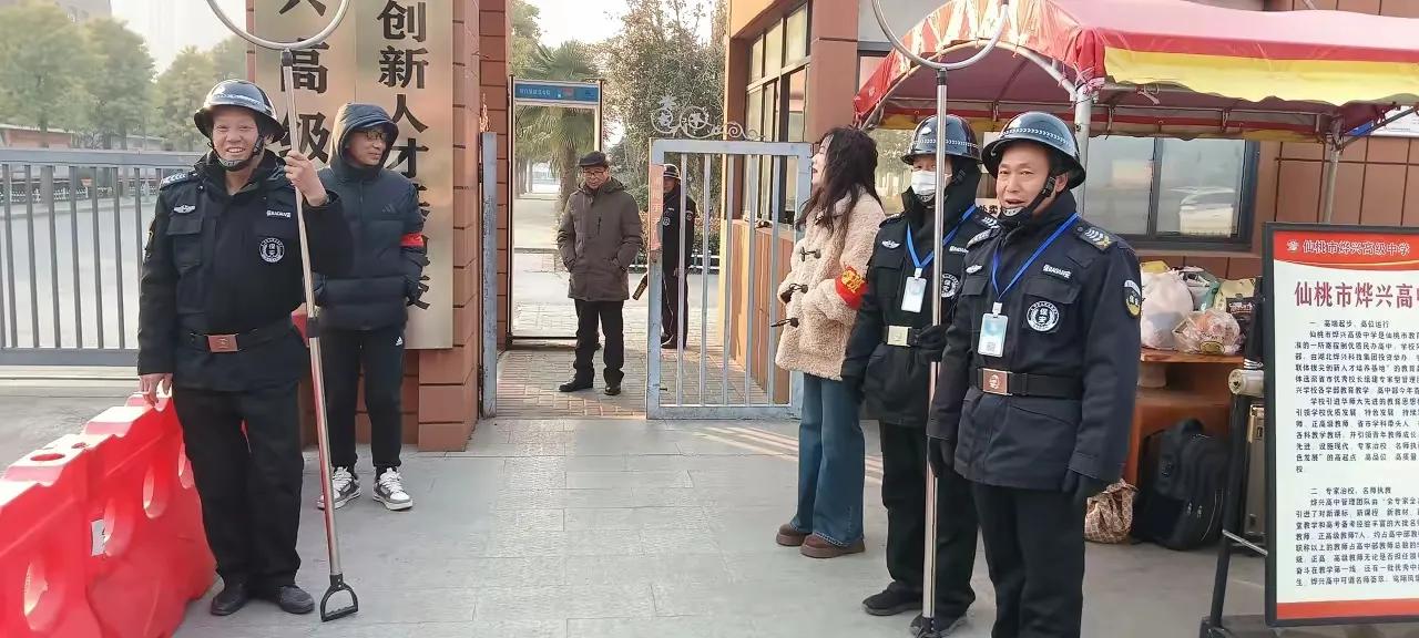 一学校门口迎接学生上学时的情景，保安们“全副武装”，学校领导也站门口迎接，学生们