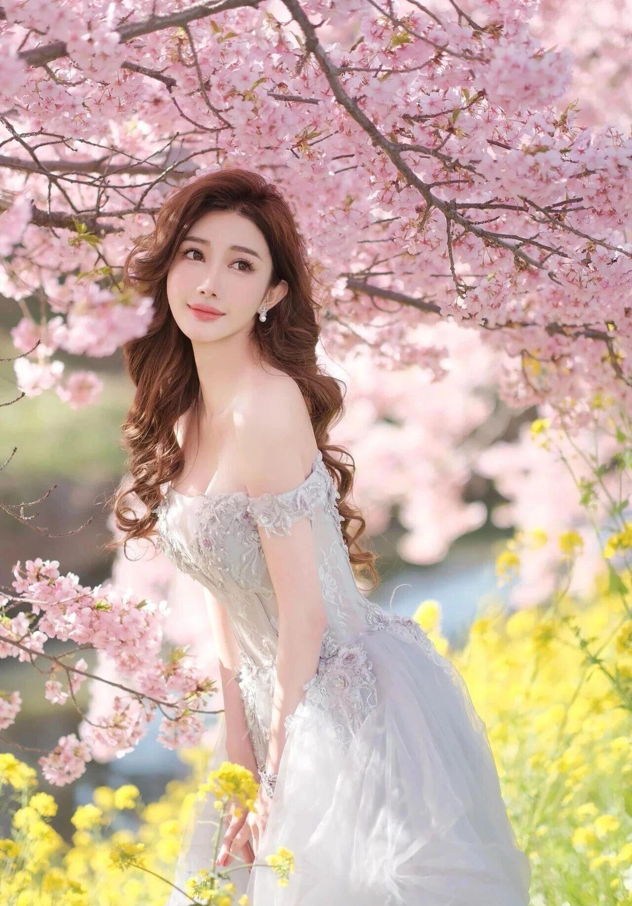 场景氛围：春日樱花大道，粉白樱花如云似霞，搭配嫩黄油菜花与翠绿草地，光影通透，呈